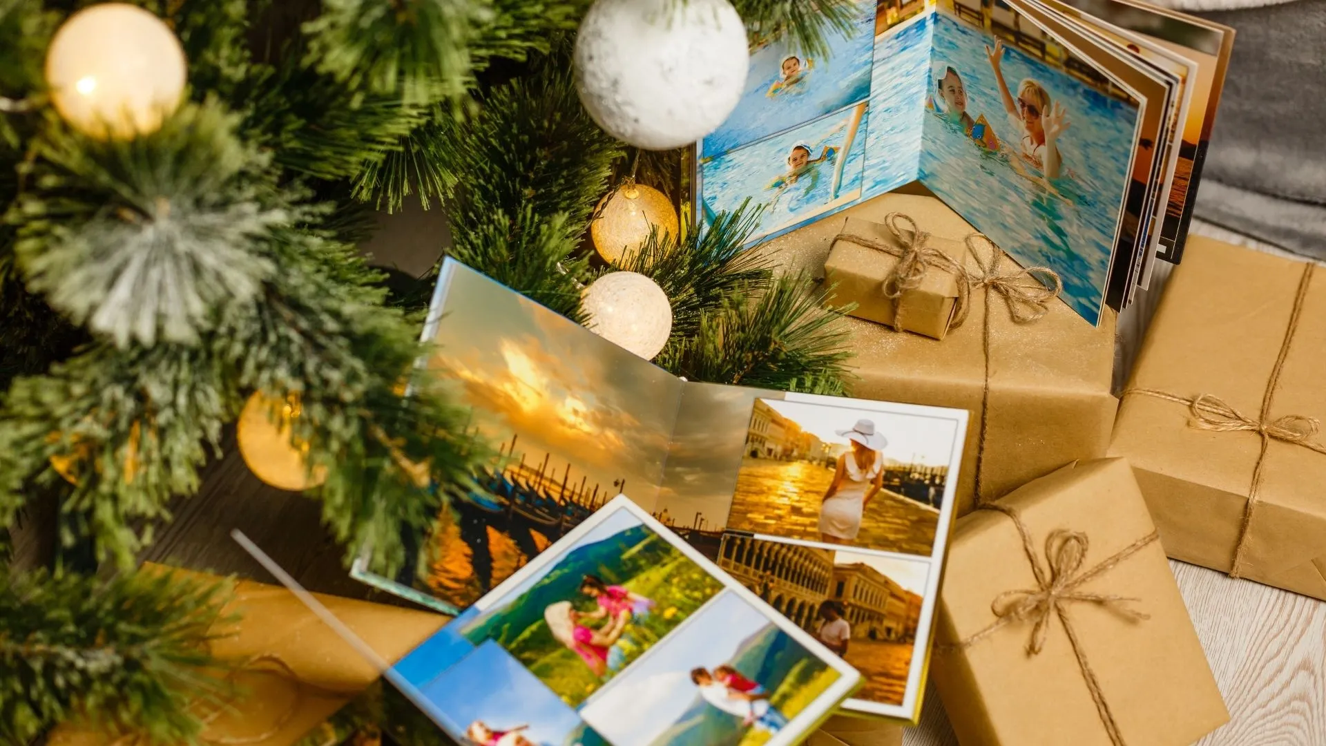Uppslagna fotoböcker bland inslagna julklappar under en julgran